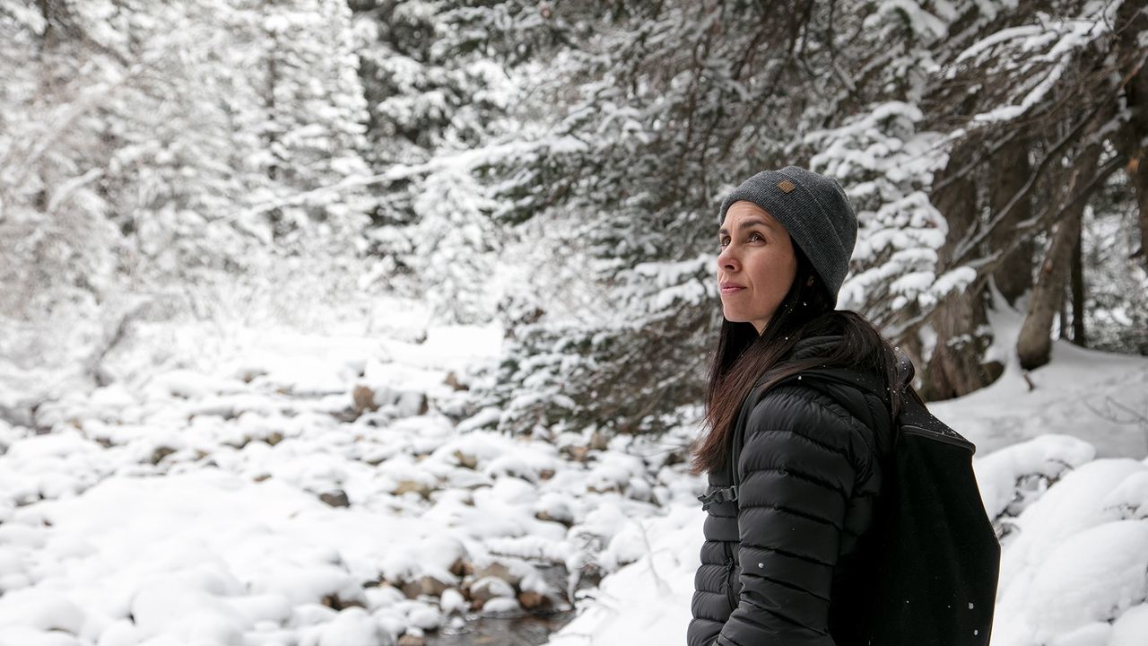 Eine Frau geht durch einen verschneiten Wald