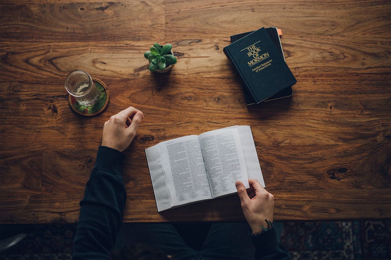 Ein Mann liest am Küchentisch in der Bibel und im Buch Mormon