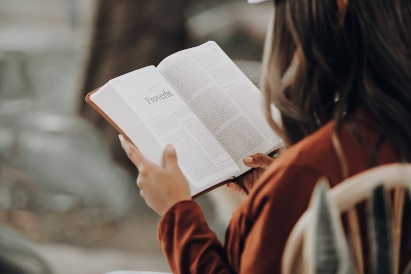 Eine Frau liest im Buch der Sprichwörter in der Bibel