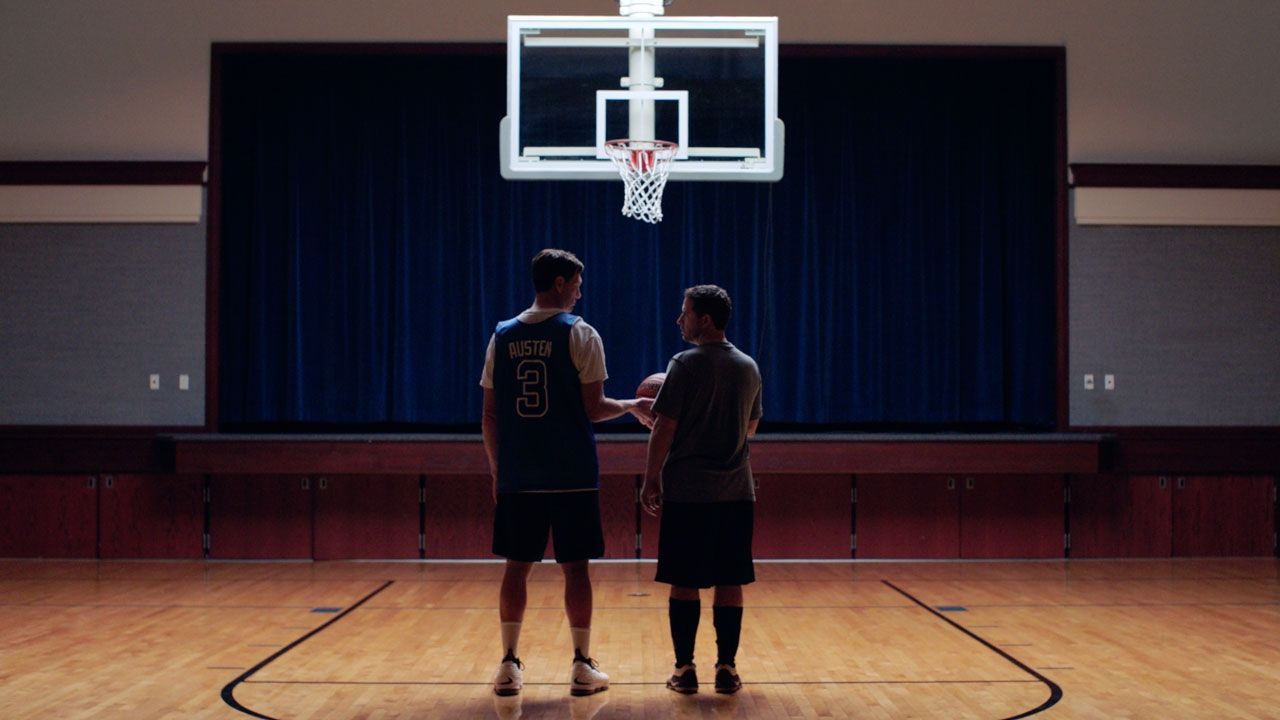 Zwei Männer stehen nebeneinander unter einem Basketballkorb