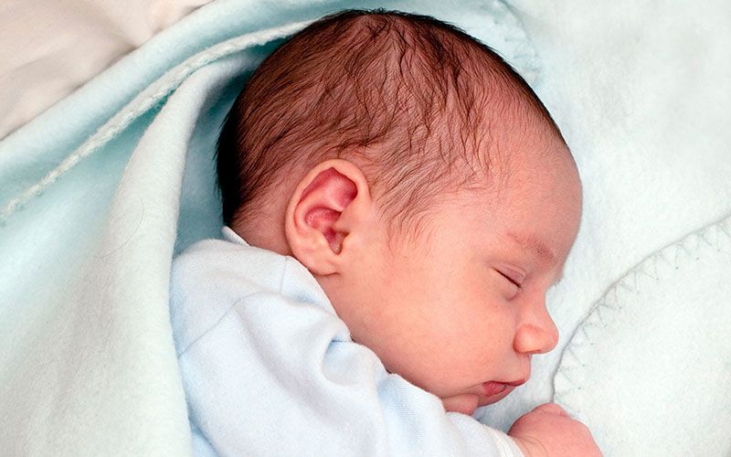 Ein schlafendes Neugeborenes, das in eine Decke gewickelt ist